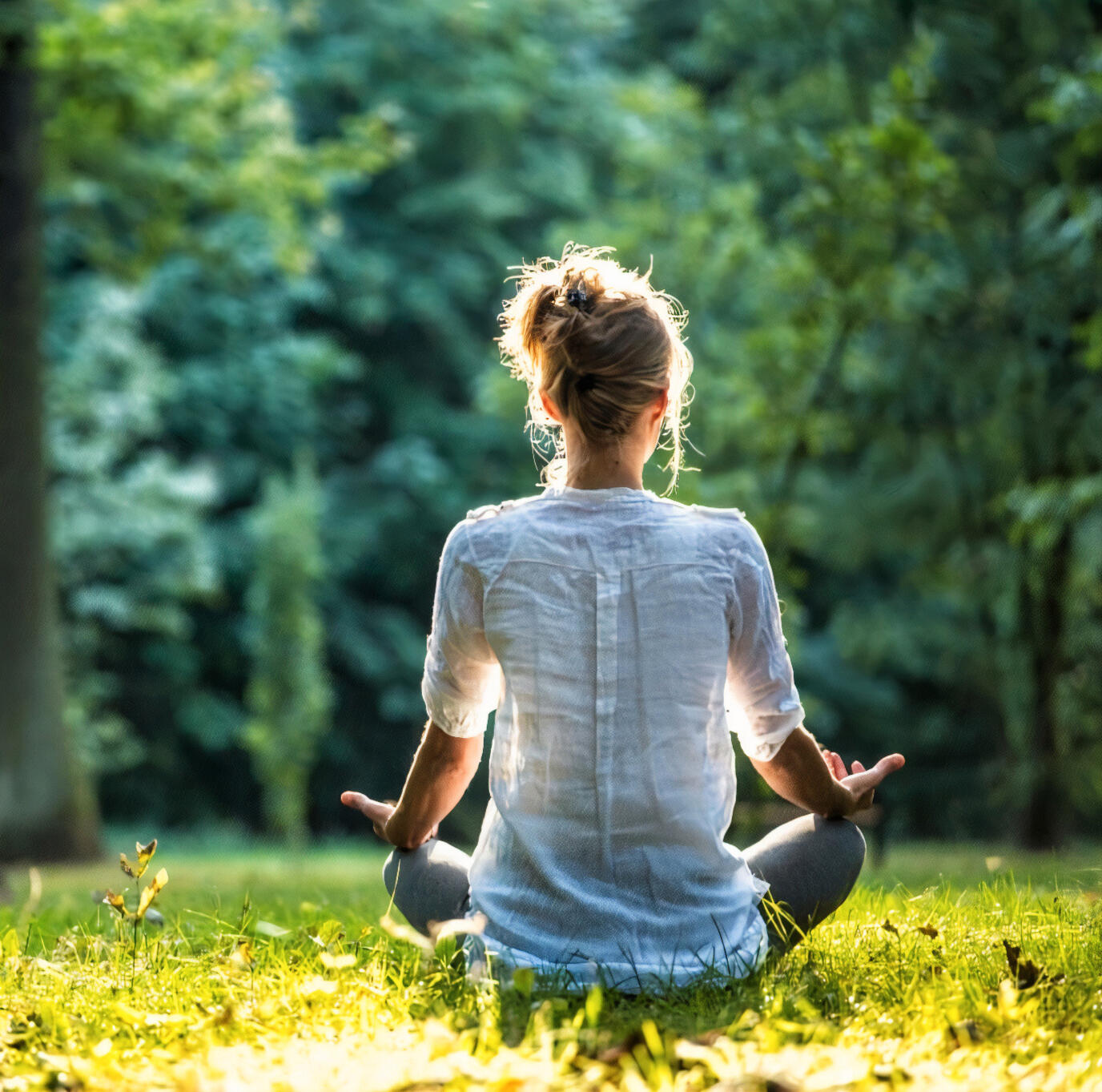 Femme apaisée méditant dans l'herbe – hypnose et sérénité à Paris 19ᵉ